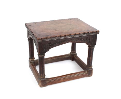 An Antique oak joint stool, having carved top and frieze, raised on octagonal column supports united by stretchers, 40cm