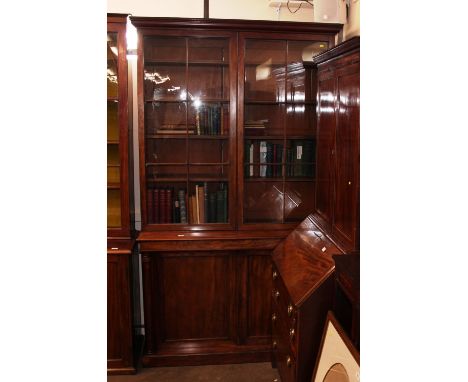 A 19th Century mahogany bookcase, the upper adjustable shelves enclosed by a pair of panelled doors above cupboard base, rais