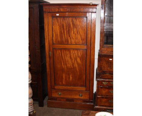 A Victorian mahogany single hanging wardrobe, enclosed by a panelled door, fitted single drawer below, raised on a platform p