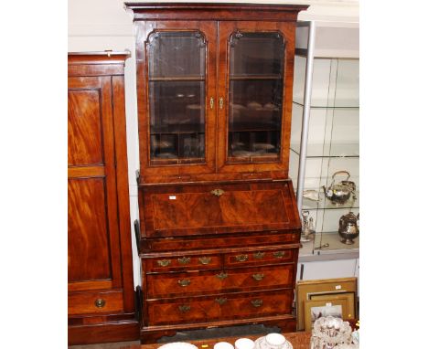 An 18th Century walnut bureau bookcase, the upper adjustable shelves enclosed by a pair of bevelled glazed panelled doors, en