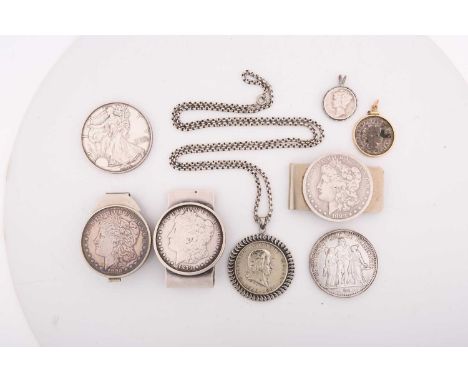 A collection of coins and money clips including a mounted Austrian two schilling commemorating the 175th anniversary of birth