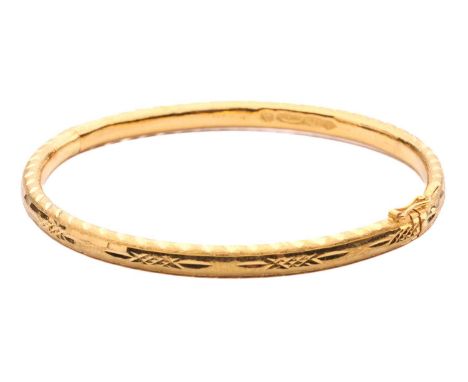 A high-carat hinged bangle, decorated with textures and bright-cut engravings, fastens with a concealed tongue clasp and figu