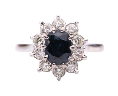 A sapphire and diamond cluster ring, centred with an oval-cut sapphire of dark greenish-blue, measuring 7.7 x 5.7 x 4.8 mm, c