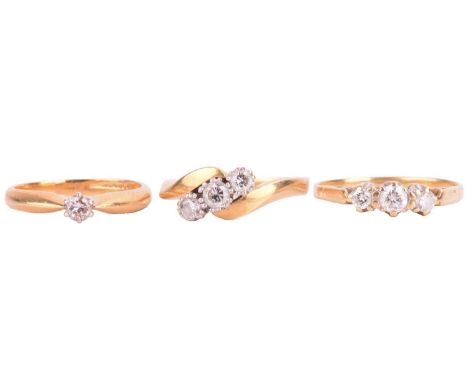 Three diamond-set rings in 18ct gold; the first has a crossover style and set with three diamonds in between, London 1990, si