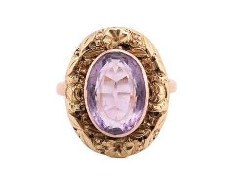An amethyst dress ring, comprising an oval-cut amethyst of light purple colour, collet-set within a surround chased with flor