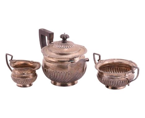 A late Victorian silver three-piece tea service, the teapot with wooden knop and handle, half-reeded decoration with gadroone