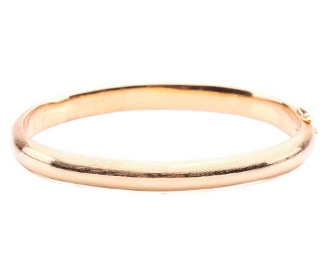 A yellow metal bangle; brushed finish, with a hinged opening and concealed push button clasp. Marked '750'. 20.5 grams