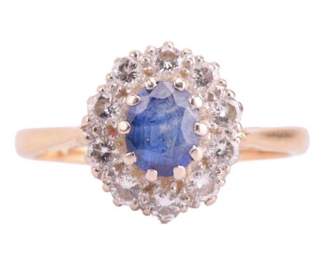 A sapphire and diamond halo ring in 18ct gold, centred with an oval-cut sapphire with bright blue colour, encircled by ten br