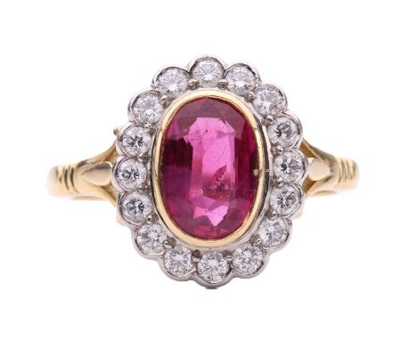 A ruby and diamond halo ring, centred with an oval-cut ruby of bright pinkish-red colour, approximately measures 8.9 x 5.9 x 