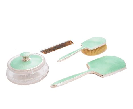 A 1930s silver and enamel dressing table set, comprising a silver backed mirror, brush and jar lid, each decorated with green