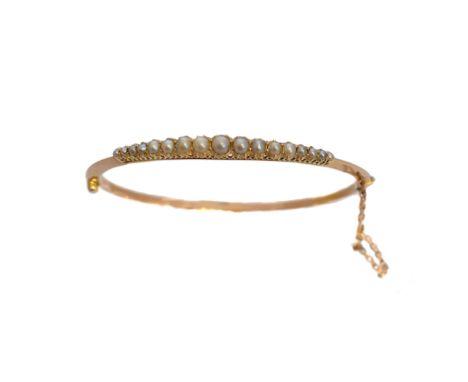 An early 20th century split pearl hinged bangle, the graduated split pearl line with polished hinged reverse, inner diameter 