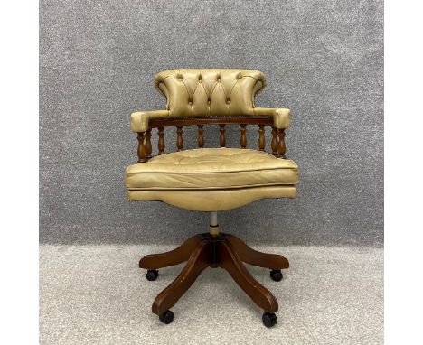 A late 20th century Captain's swivel desk chair with a sand coloured scrolled leather button back and arms over a gallery of 