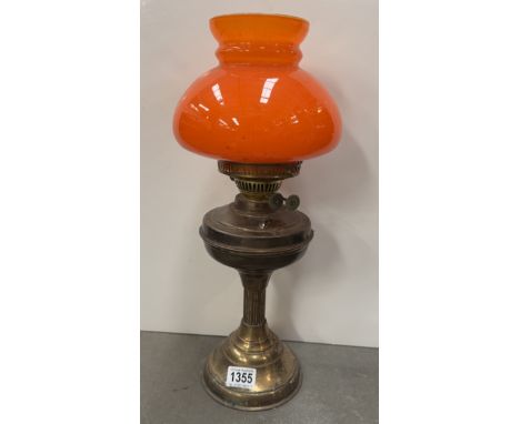 A brass oil lamp with overlaid orange on white glass shade