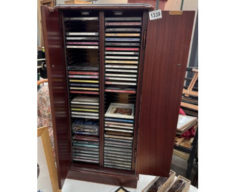 A dark wood stained CD cabinet with contents of CDs