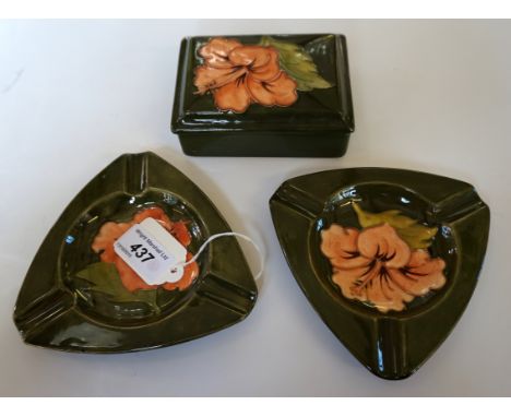 Three pieces of Moorcroft pottery decorated in the Hibiscus pattern, comprising a pair of triangular ashtrays, length 13.5 cm