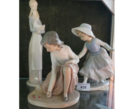 A group of three Nao Lladro figures to include a model of a girl playing marbles, a lady holding a duck, and a further lady f