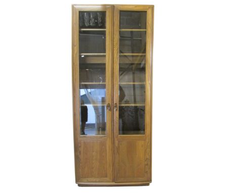 An Ercol elm upright bookcase, enclosed by a pair of full length doors, three quarter glazed, with adjustable shelves, 215cm 