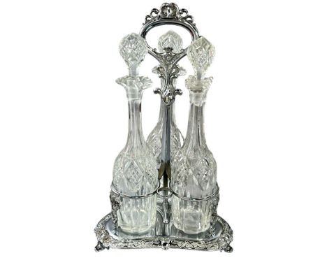 A Victorian silver plated three decanter cruet with central scrolled handle accommodating three bottles, 43cm high