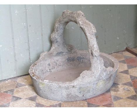 A novelty weathered cast composition stone planter in the form of an oval basket with rustic handle, 48cm high x 59 x 50 cm