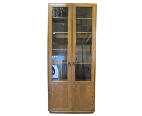 A Ercol elm upright bookcase, enclosed by a pair of full length doors, three quarter glazed, with adjustable shelves, 215cm h