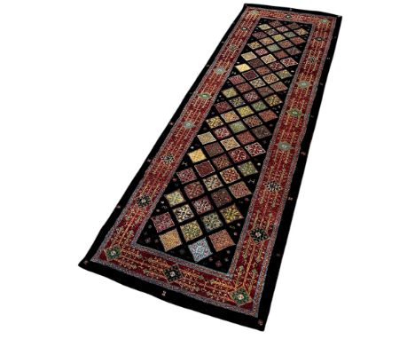 A Middle Eastern designed machine made runner with an all over diamond pattern on a dark ground 250cm x 82cm approximately 