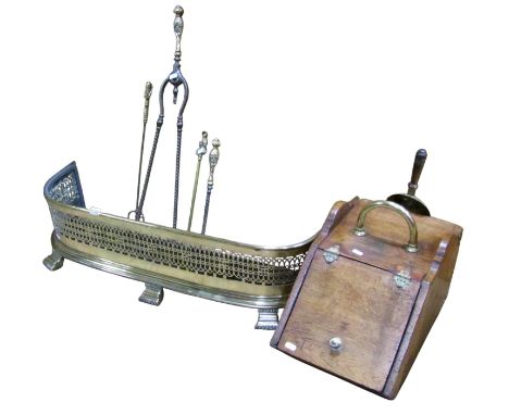 A polished brass fender with pierced grill, 22cm high x 88cm wide, four brass fire tools, and an oak coal scuttle (6)
