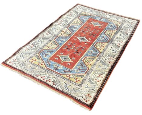 A Turkish rug with a central pink panel with three diamond medallions, 190cm x 130cm approximately