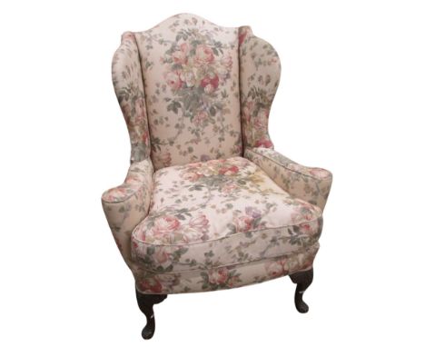 A George I style wing armchair raised on carved forelegs, with country house floral bouquet upholstery