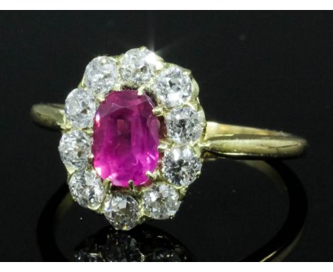 A modern gold coloured metal mounted ruby and diamond ring, the central oval cut ruby approximately .80ct contained within a 