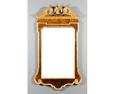 An 18th Century walnut and gilt rectangular wall mirror, the moulded scroll pediment with carved leaf ornament and central ea