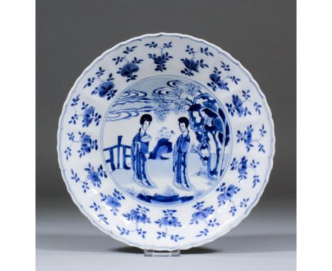 A Chinese blue and white porcelain moulded dish painted in underglazed blue with two standing female figures in a landscape, 