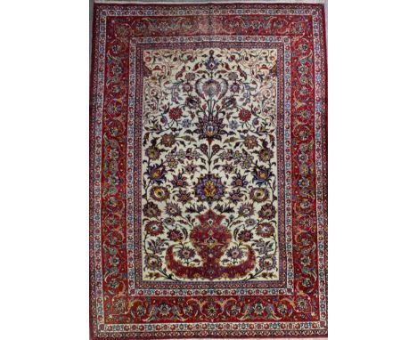 An Isphahan carpet woven in colours with a bold central urn motif and the field filled with palmettes and trailing leaf ornam