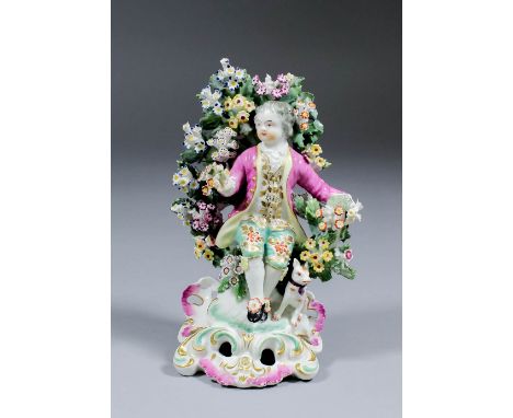 An 18th Century Derby porcelain figure of a seated boy with posy against a bocage backdrop, on high rococo base, 6.75ins high