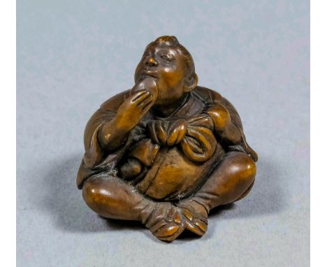 A Japanese carved boxwood netsuke in the form of a seated traveller with bulbous sack on his back, 1.125ins (28mm) high, sign
