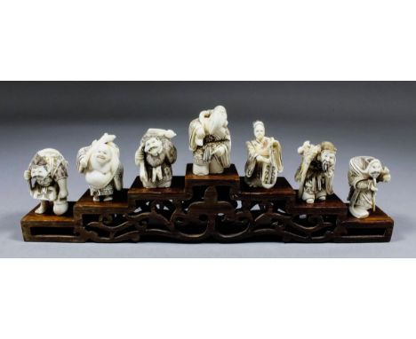 A Japanese carved ivory netsuke of Putai carrying a sack, 1.75ins (44mm) high, and six other ivory netsukes and stepped and p