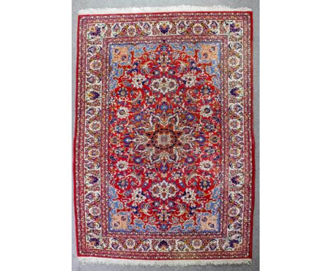 An Isphahan carpet woven in colours with a bold central circular medallion and trailing floral palmettes on a terracotta grou