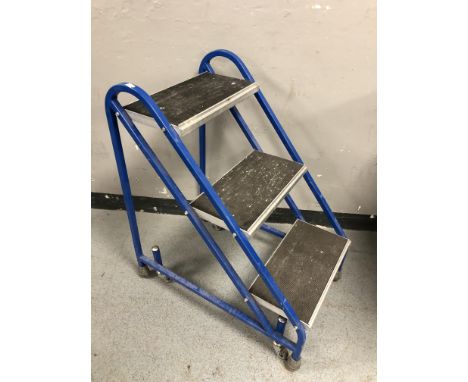 A three tread step on castors, height 79 cm.