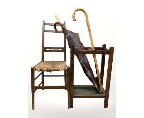An Edwardian oak umbrella stand containing walking stick, two umbrellas, together with a rush seated chair.
