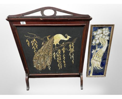 A mahogany embroidered fire screen depicting a peacock, height 86 cm and a further set of three framed tiles 
