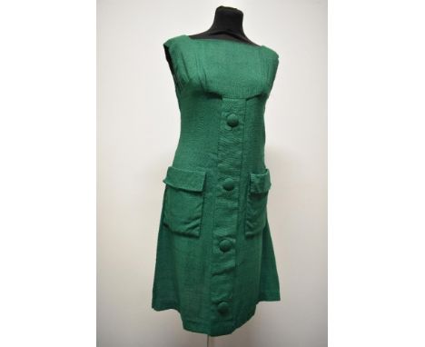 An early 1960s emerald green linen mini dress, having large self covered faux button detail to front, two patch pockets, plea