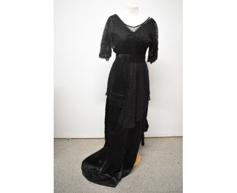 A black Edwardian gown, having sash to waist with tassel detail, lace bodice and overlay to skirt and black beading to neckli