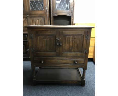 A Chapmans Siesta oak double door linen fold cabinet fitted a drawer 