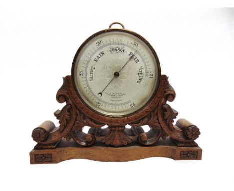 AN ANEROID BAROMETER  the silvered dial inscribed 'S & J Hicks HATTON GARDEN LONDON' 21cm diameter,  on carved oak base 41cm 
