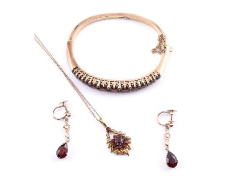 
	
		A 9 CARAT GOLD GARNET BANGLE 
		LONDON 1973
		The bangle set with a row of circular cut garnets, to a polished back with