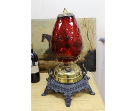 A floor-standing cranberry glass, brass and iron-mounted lamp, converted to a table lamp, 63cms high