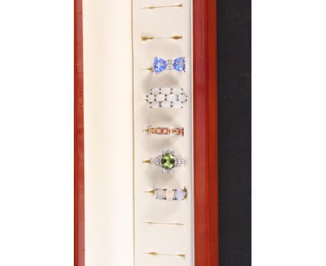 A ring box (in as new condition) with five silver stone set rings including sapphire, blue topaz, opal and peridot, all with 