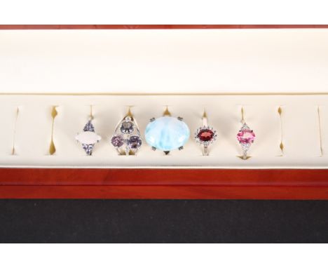 A ring box (in as new condition) with five silver stone set rings including opal, spinel, larimar, garnet and pink topaz, all