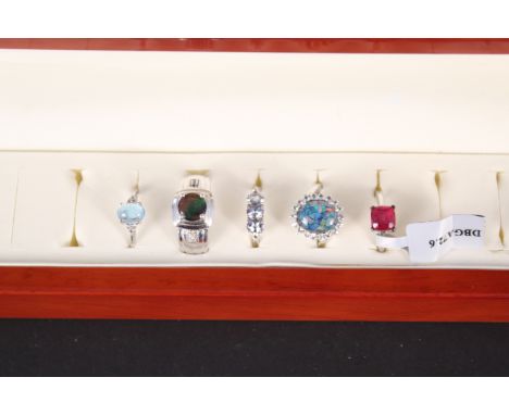 A ring box (in as new condition) with five silver stone set rings including opal, blue topaz, ammolite, tanzanite and ruby, a