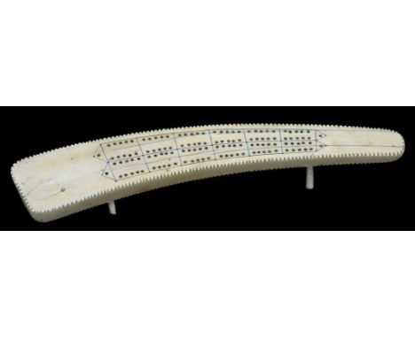 A VICTORIAN IVORY CRIBBAGE BOARD CARVED FROM A SECTION OF TUSK, 34CM L