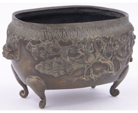 A Chinese oval bronze pot,with relief cast peacock and blossom tree designs, length including handles 8", height 4.75".